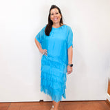 Woman wearing the Gail tiered ruffle dress in turquoise with a flowy silhouette and layered ruffle details.
