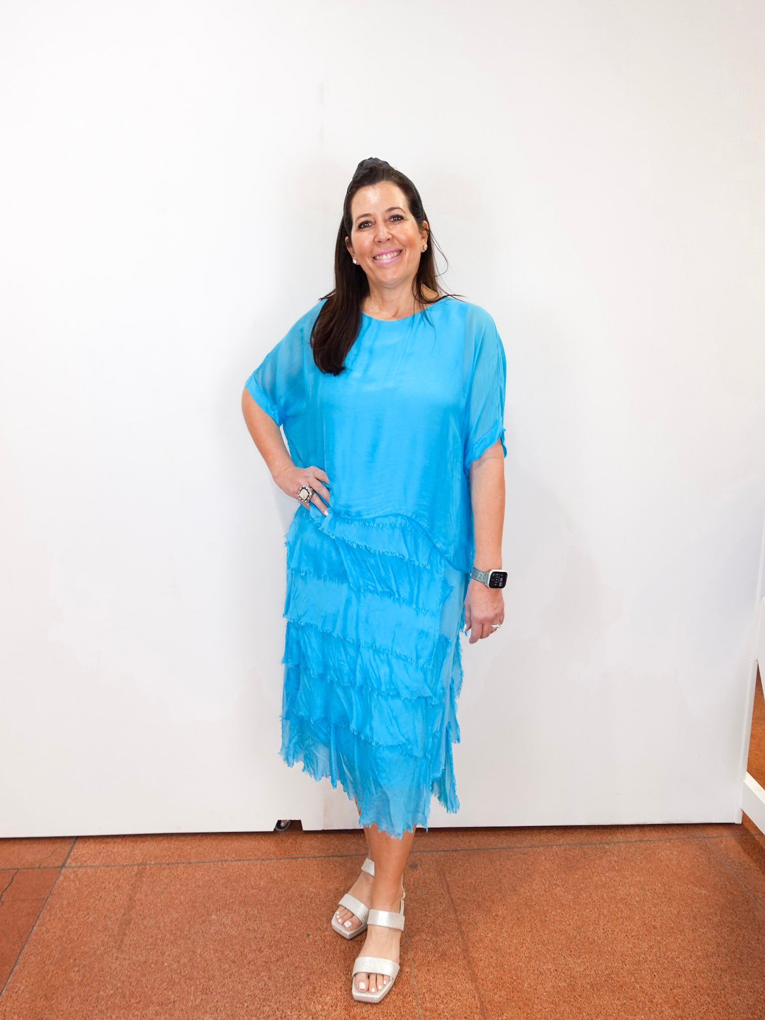 Woman wearing the Gail tiered ruffle dress in turquoise with a flowy silhouette and layered ruffle details.