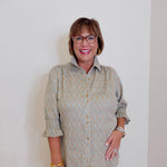 Woman wearing a patterned shirt and glasses against a plain background