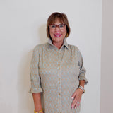 Woman wearing a patterned shirt and glasses against a plain background