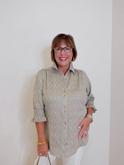 Woman wearing a patterned shirt and glasses against a plain background