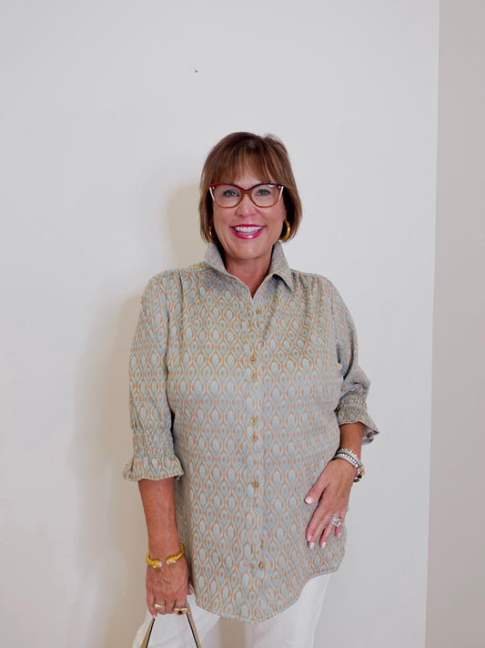 Woman wearing a patterned shirt and glasses against a plain background