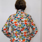 Person wearing a colorful bird-patterned shirt against a white background