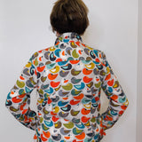 Person wearing a colorful bird-patterned shirt against a white background