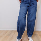 Person wearing blue jeans and white sneakers on a plain background