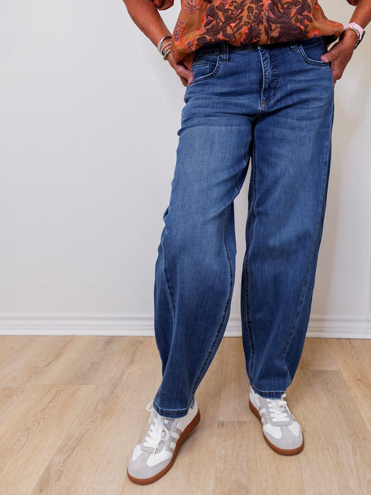 Person wearing blue jeans and white sneakers on a plain background