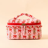 Floral and bow-patterned fabric suitcase with red accents on a beige background