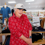 Woman wearing a red star-patterned shirt and white cap in a store setting
