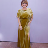 Woman wearing a gold velvet flutter sleeve maxi dress featuring a relaxed fit, waist detail, and side slit.