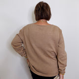 Person wearing a beige sweater against a white wall