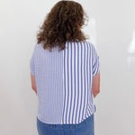 Person wearing a blue and white striped shirt and blue jeans against a white background