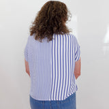 Person wearing a blue and white striped shirt and blue jeans against a white background