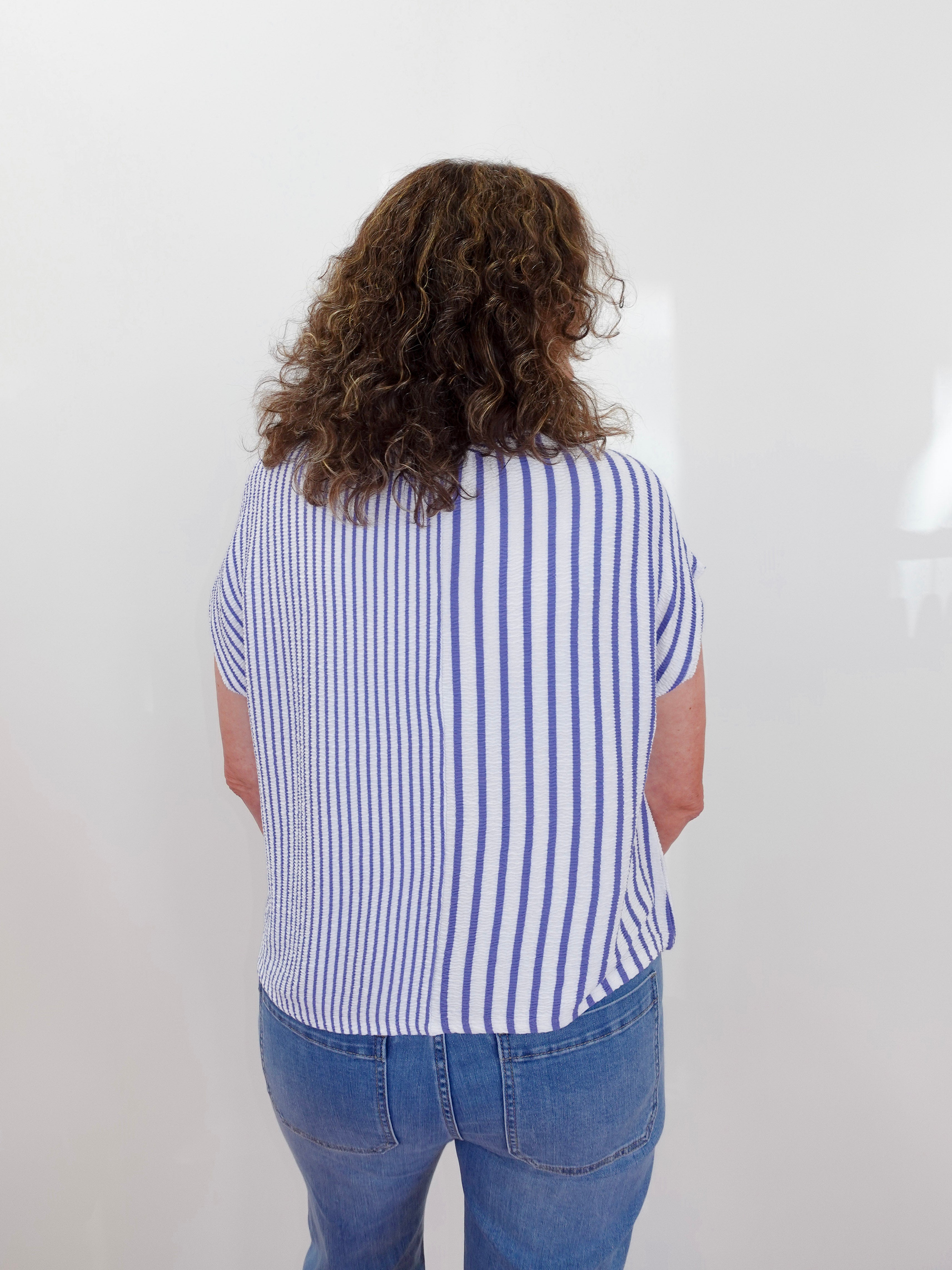 Person wearing a blue and white striped shirt and blue jeans against a white background
