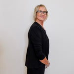 Person wearing a black outfit against a plain background