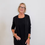Woman wearing a black outfit with glasses against a white background