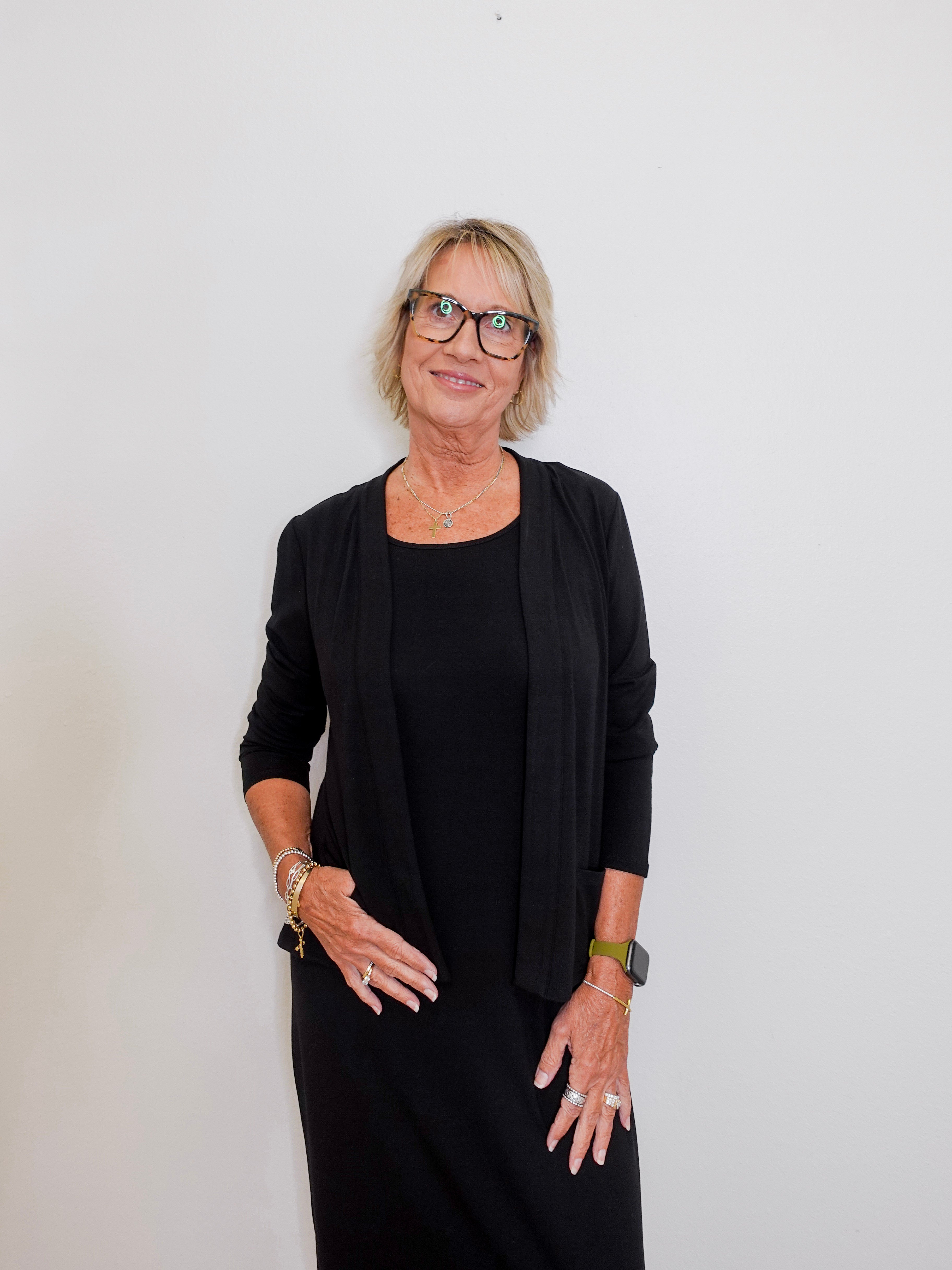 Woman wearing a black outfit with glasses against a white background