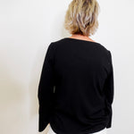 Person wearing a black top and white pants against a plain background