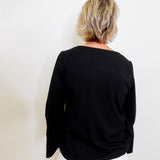 Person wearing a black top and white pants against a plain background