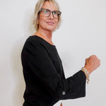 Woman wearing glasses and a black top against a white background
