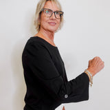 Woman wearing glasses and a black top against a white background