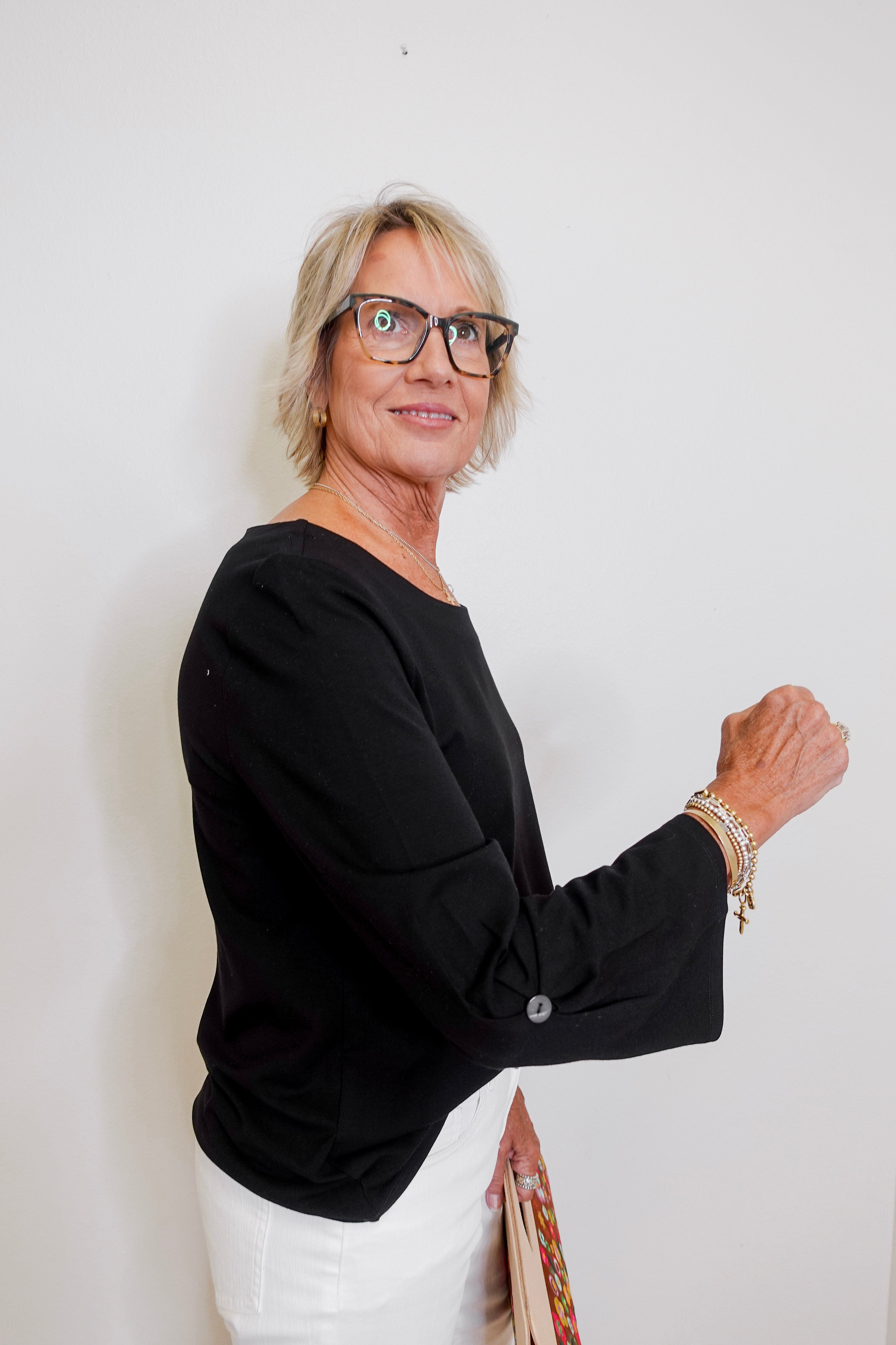 Woman wearing glasses and a black top against a white background