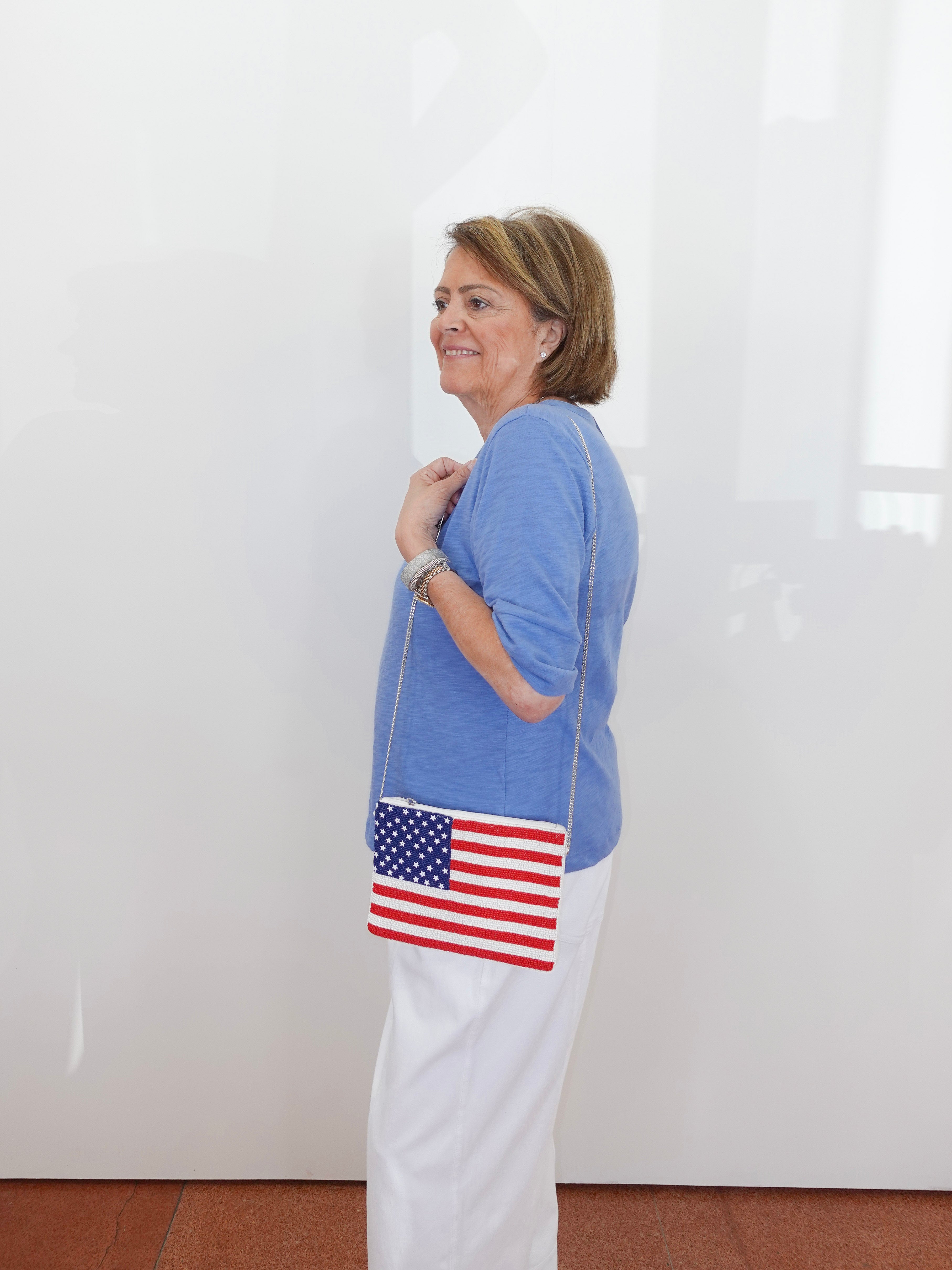 Woman holding a handbag with an American flag design against a white background