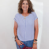 Woman wearing a blue and white striped shirt and jeans, holding a red handbag against a white background