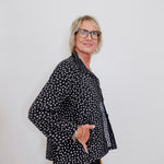 Person wearing a black polka dot shirt against a white background