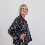 Person wearing a black polka dot shirt against a white background
