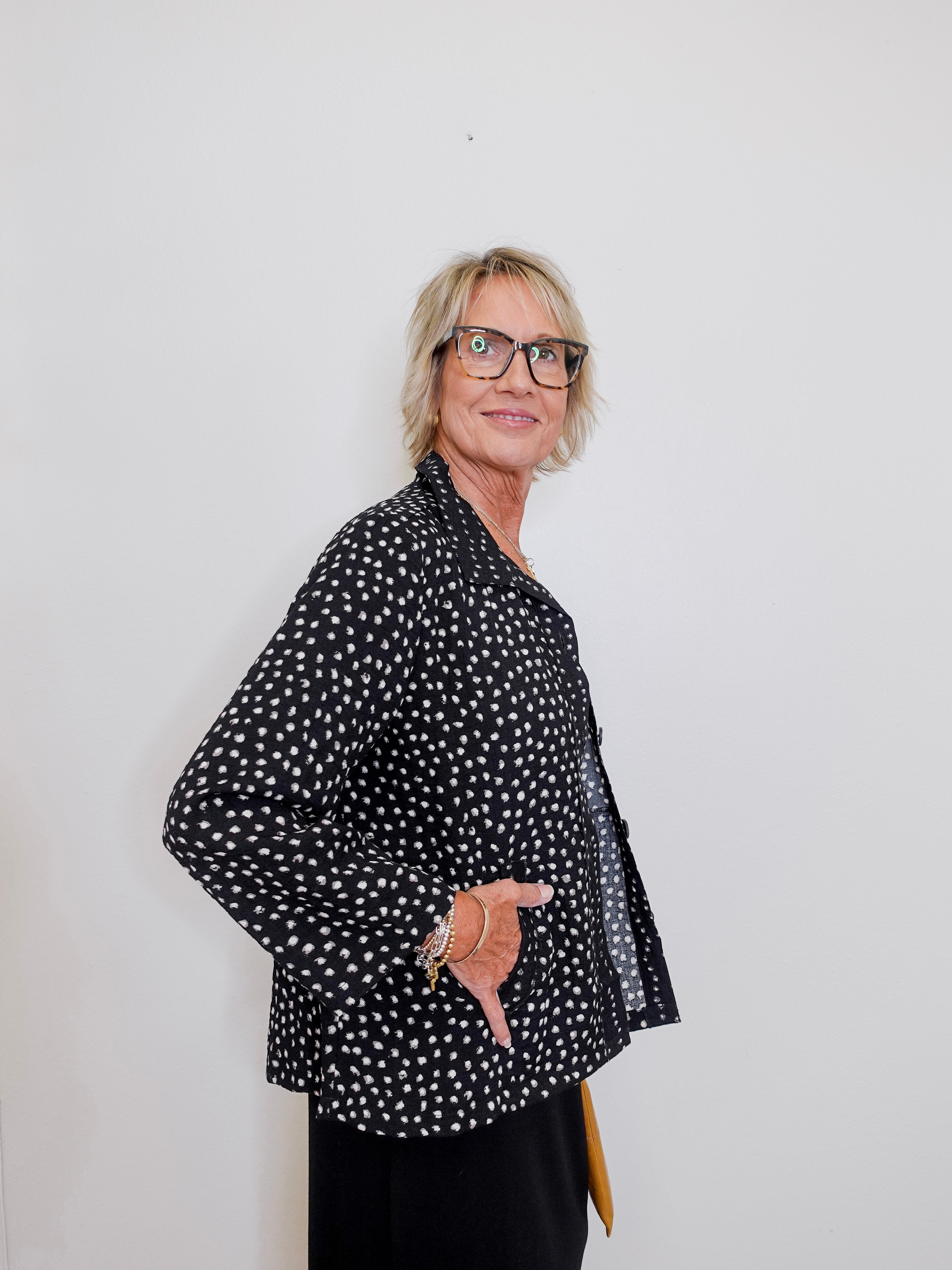 Person wearing a black polka dot shirt against a white background