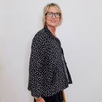 Person wearing a black polka dot shirt against a white background
