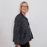 Person wearing a black polka dot shirt against a white background