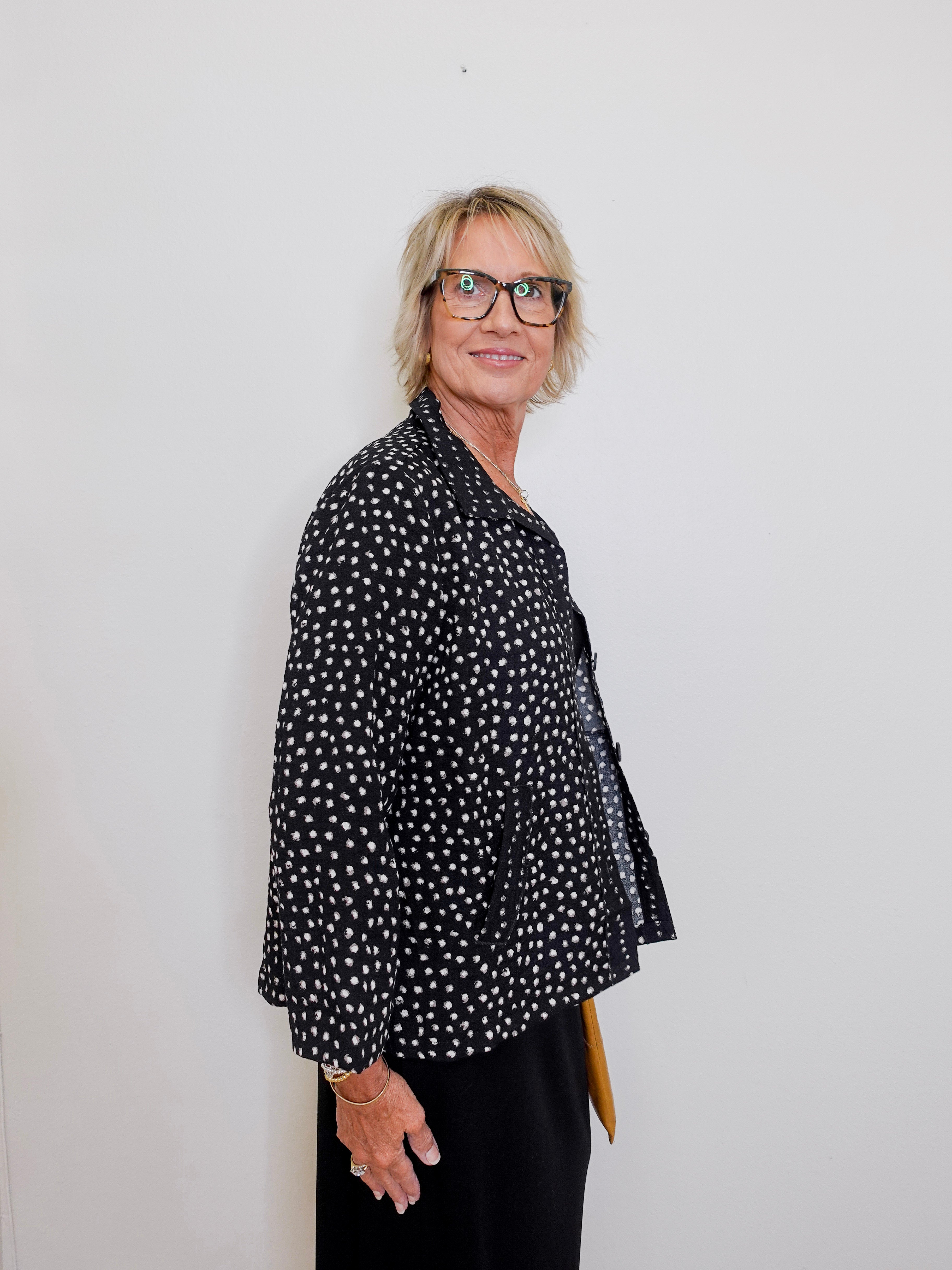 Person wearing a black polka dot shirt against a white background