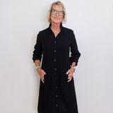 Woman wearing a black dress standing against a white wall