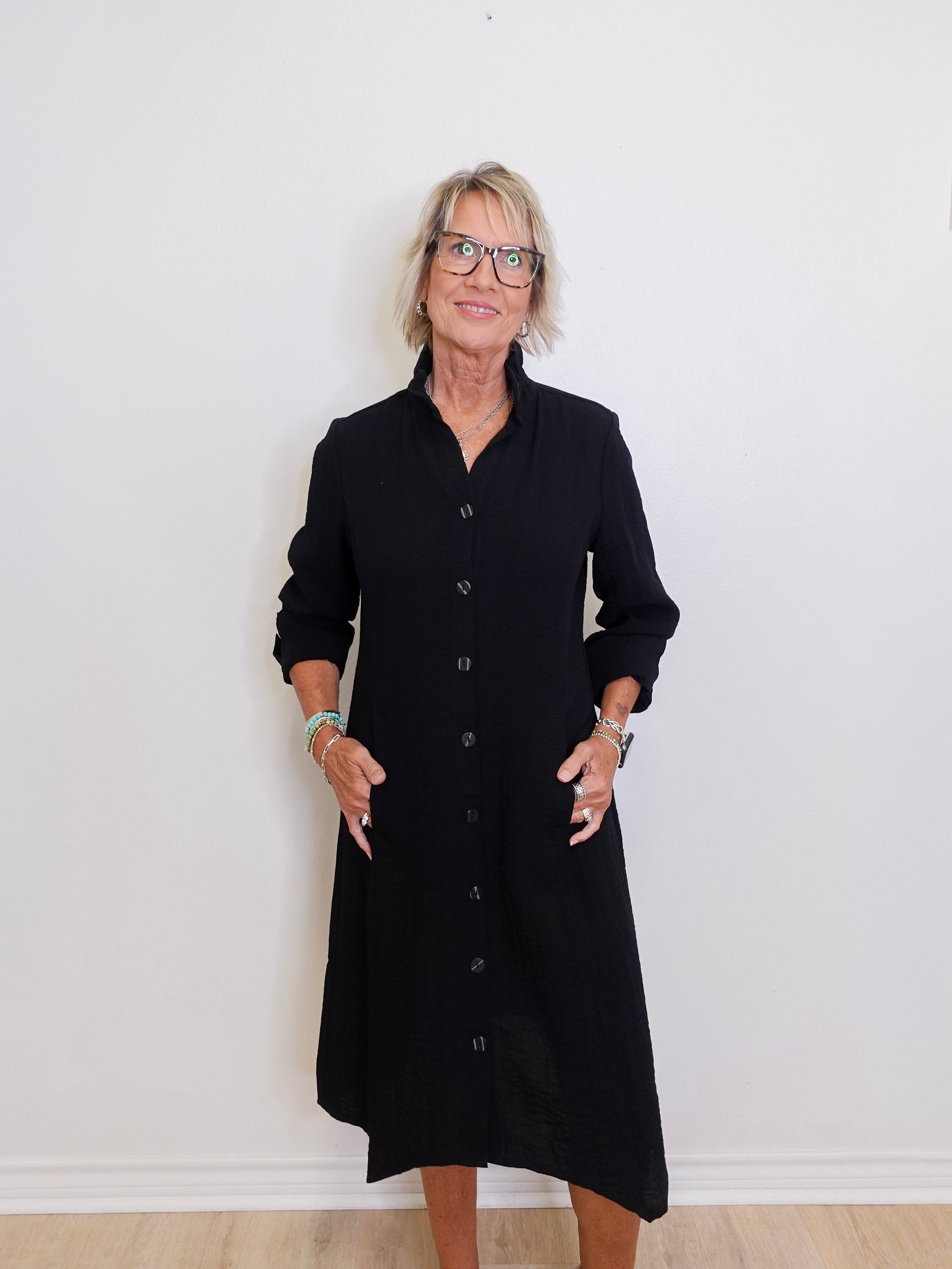 Woman wearing a black dress standing against a white wall