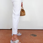 Person wearing white pants and colorful sandals on a brown floor.