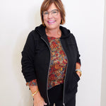 woman wearing a black jacket against a white background. 