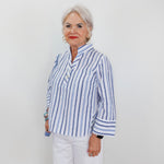 Woman wearing a blue and white striped shirt against a plain background