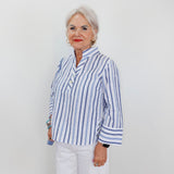 Woman wearing a blue and white striped shirt against a plain background
