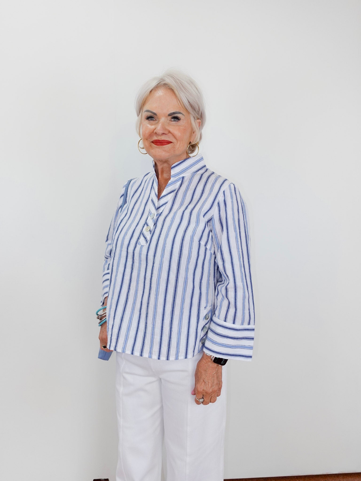 Woman wearing a blue and white striped shirt against a plain background