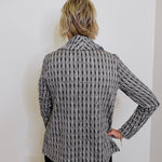 Person wearing a patterned blazer against a white wall
