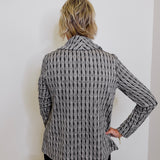 Person wearing a patterned blazer against a white wall