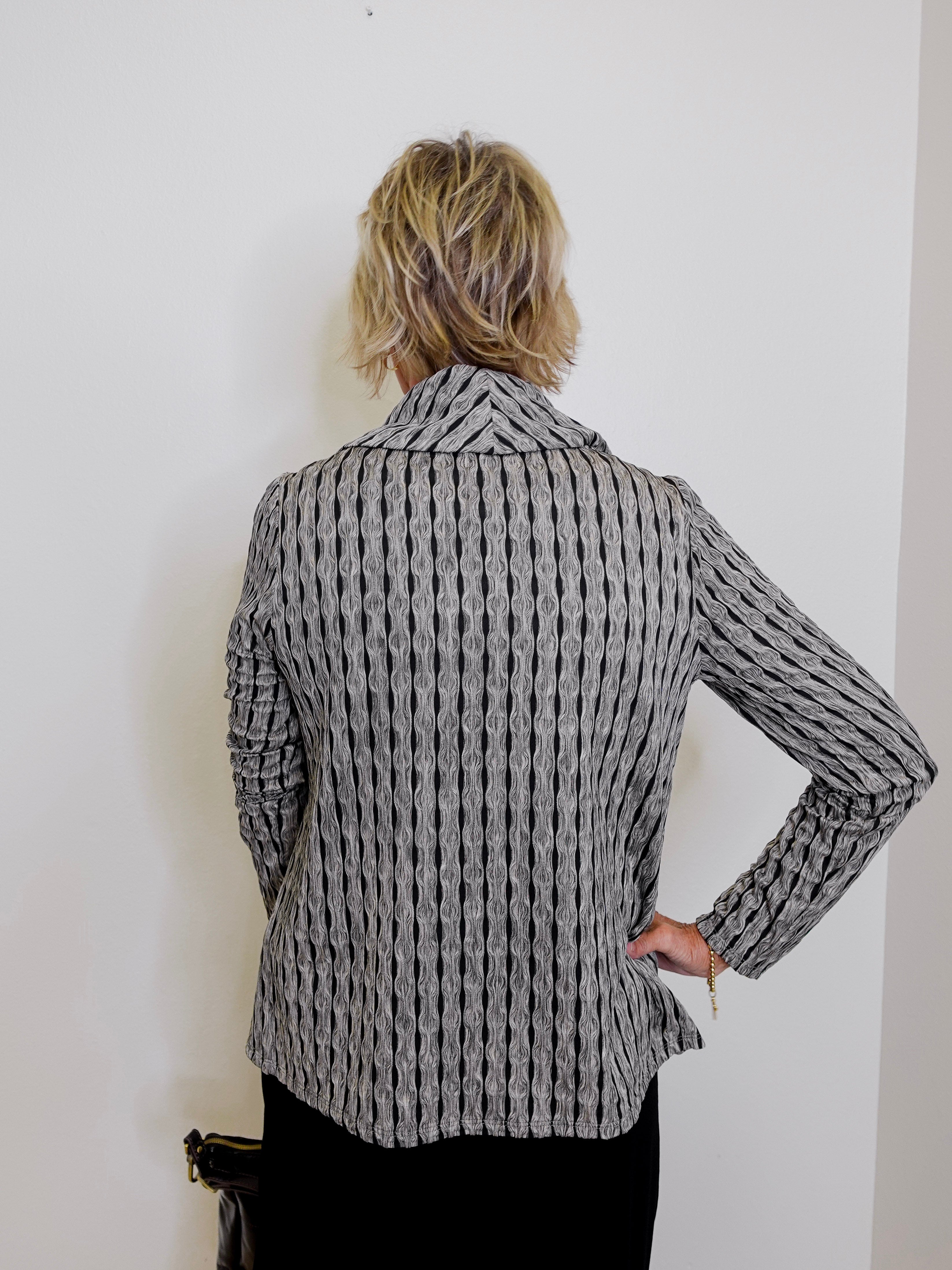 Person wearing a patterned blazer against a white wall