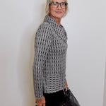Woman wearing a patterned sweater and glasses against a white wall