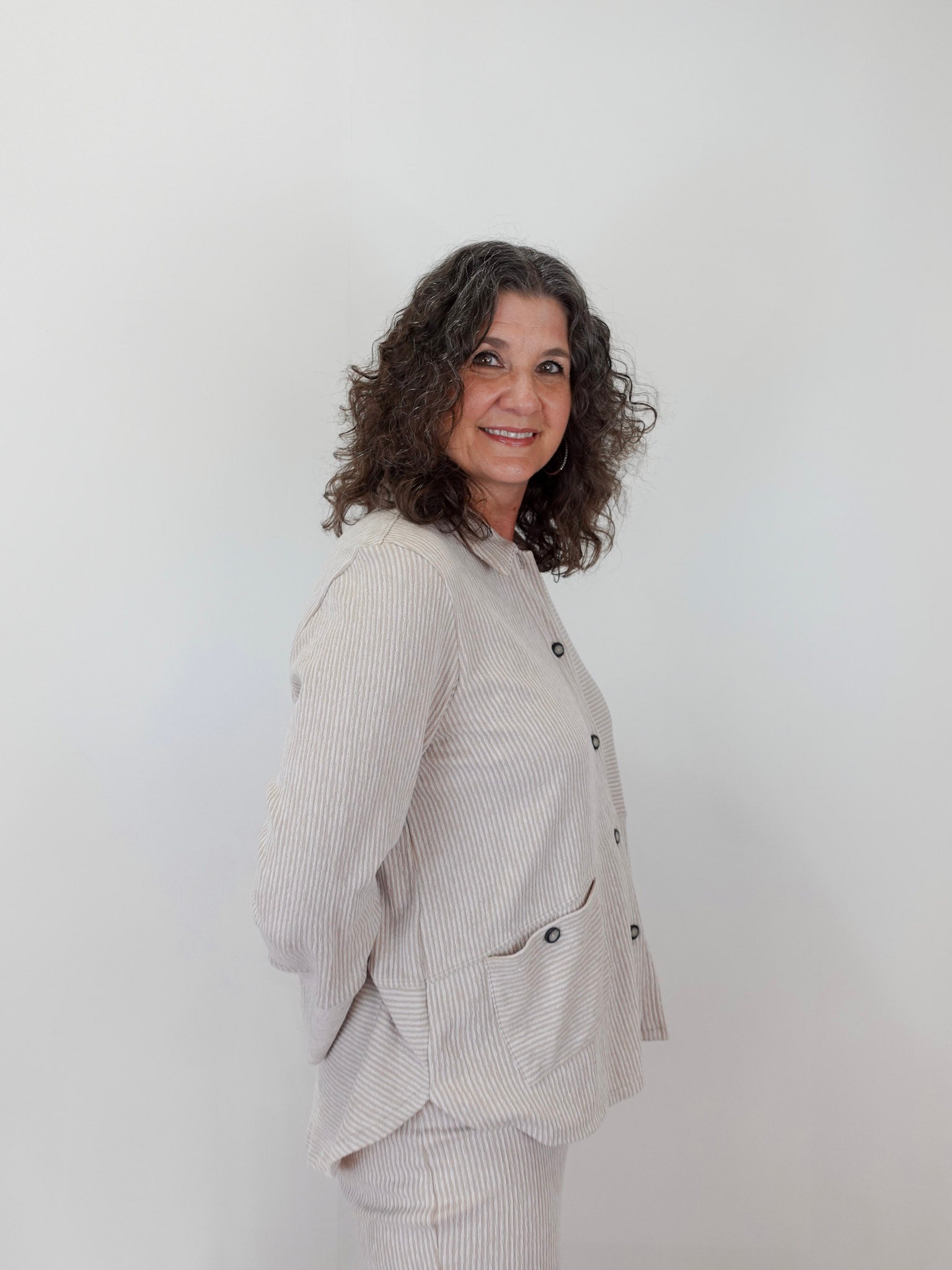 Woman wearing a light gray textured jacket against a white background