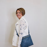Woman holding a blue bag against a plain white wall