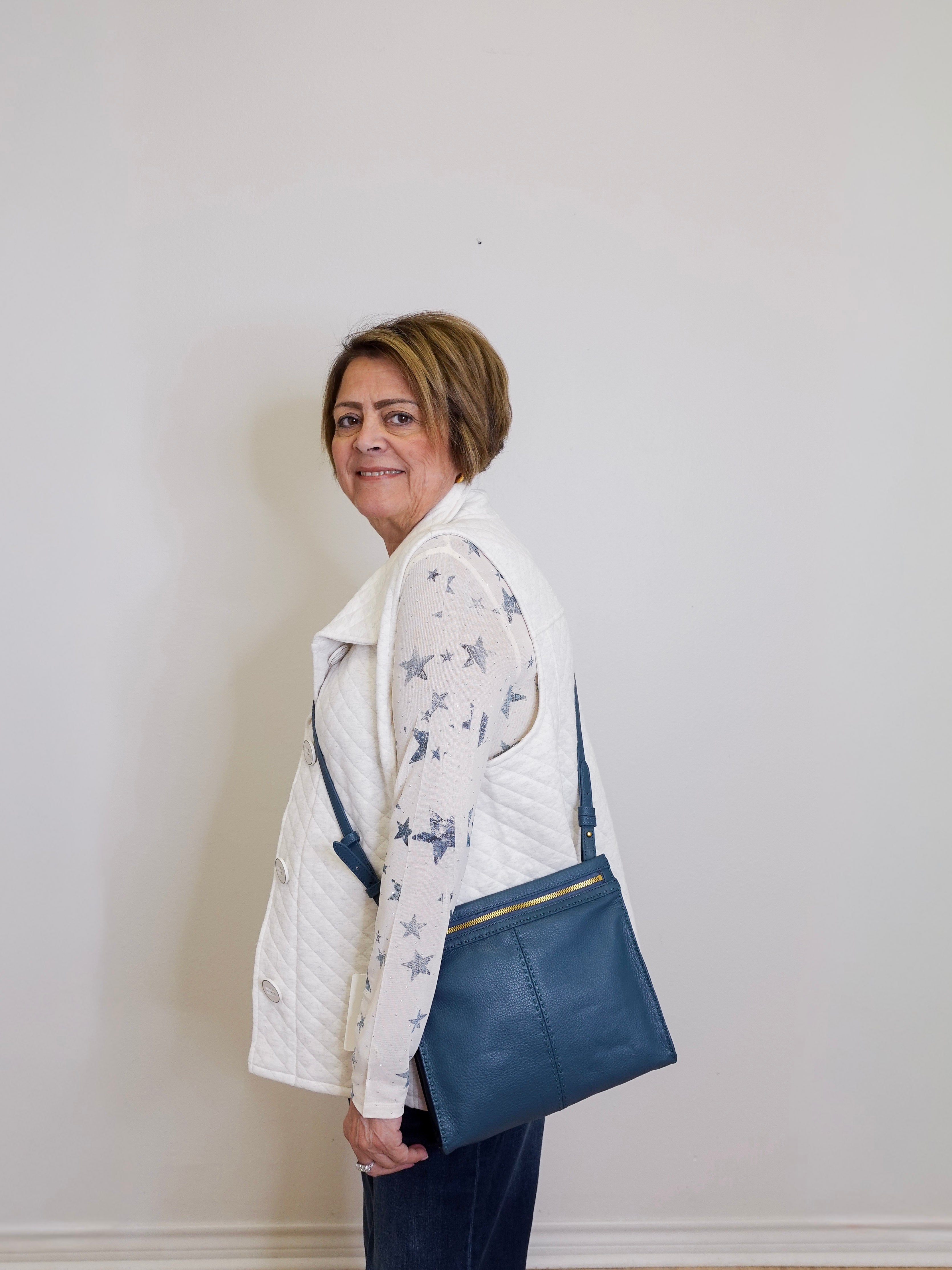 Woman holding a blue bag against a plain white wall