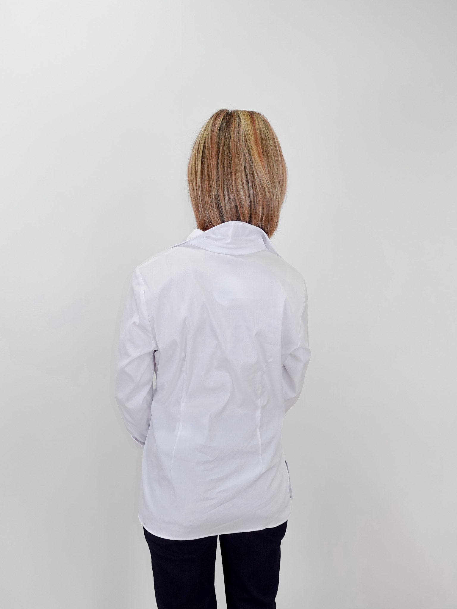 Person wearing a white lab coat against a plain background
