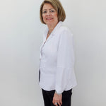 Woman wearing a white blouse and black pants against a plain background