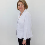 Woman wearing a white blouse and black pants against a plain background